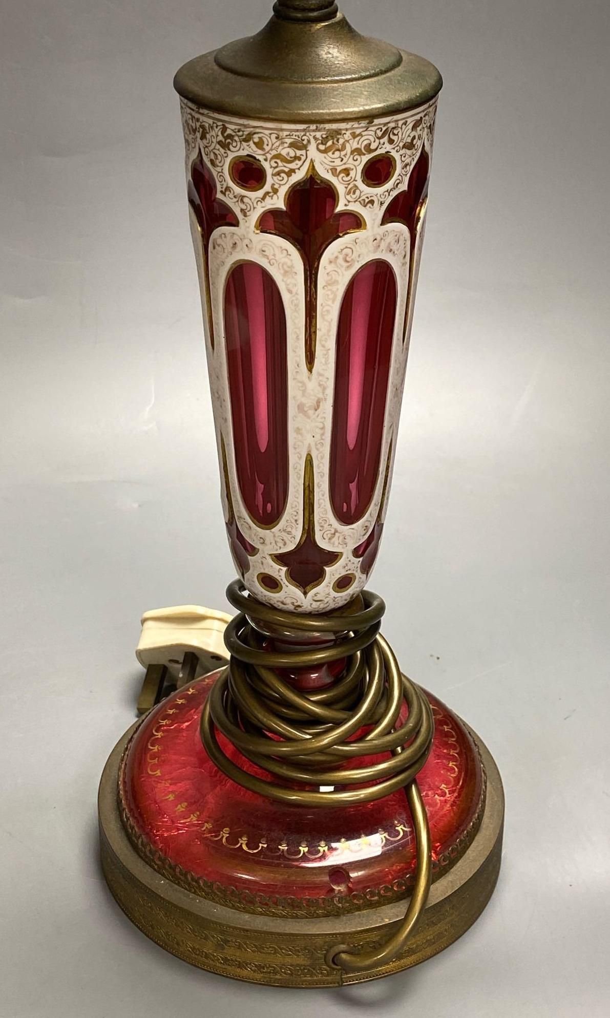 A 19th century Bohemian overlay ruby glass lamp, on engraved brass plinth, 34cm excluding light fittings
